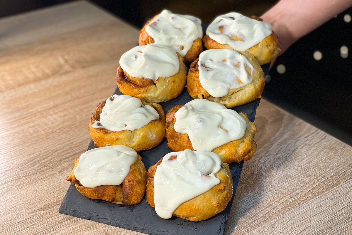 High-Protein Cinnamon Rolls with cream cheese frosting, served on a stone plate