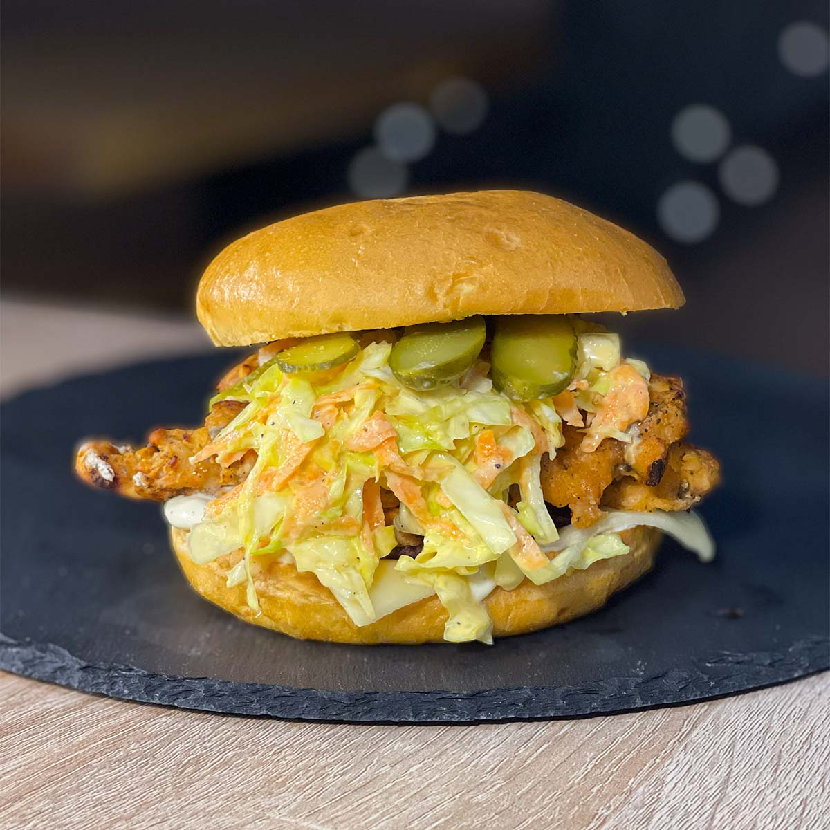 Close-up photo of a Chicken Coleslaw Sandwich (High-Protein Burger) served on a stone plate