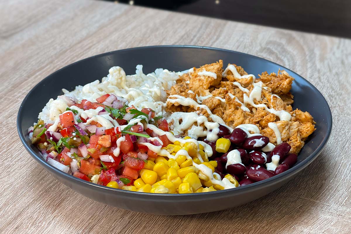 Meal Prep BBQ Chicken Burrito Bowl with rice, homemade pico de gallo, corn, kidney beans, BBQ pulled chicken and burrito bowl dressing