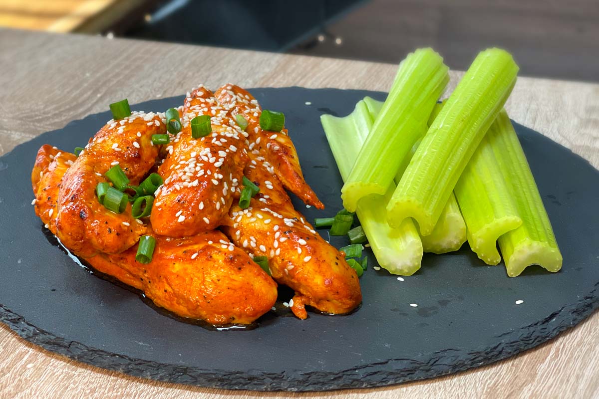 Air Fryer Buffalo Chicken Tenders without breading served with celery sticks on a stone plate.